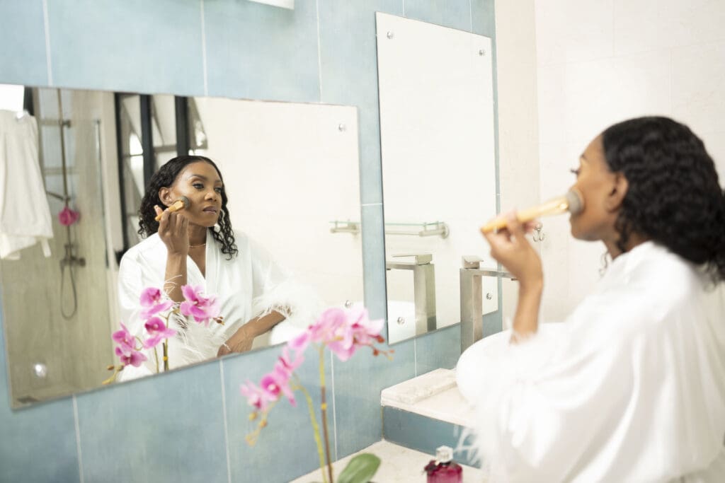 Dr Charmaine Thomas looking at her reflection in the mirror while applying makeup, used to illustrate how menopause changes often appear in the mirror first.
