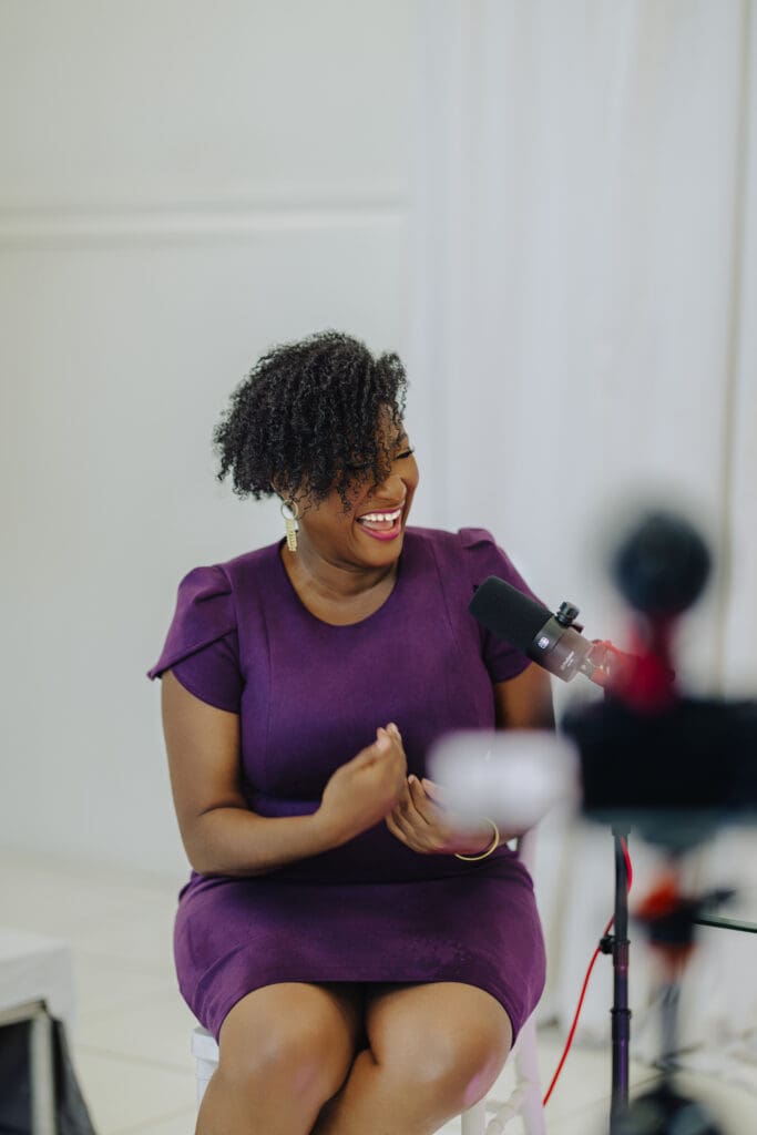 Dr Llorenia Muir-Green smiling while speaking into a podcast microphone during her guest appearance on the Menopause Rebirth Podcast.